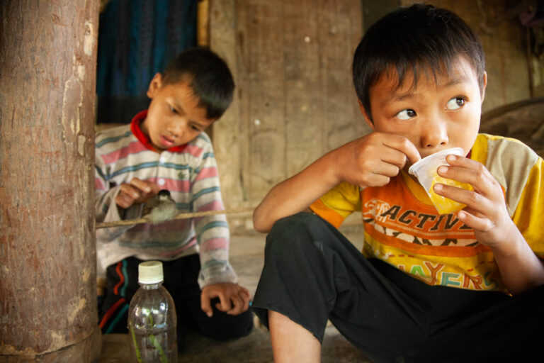 Boys eating and playing with a bird in Sapa, Vietnam