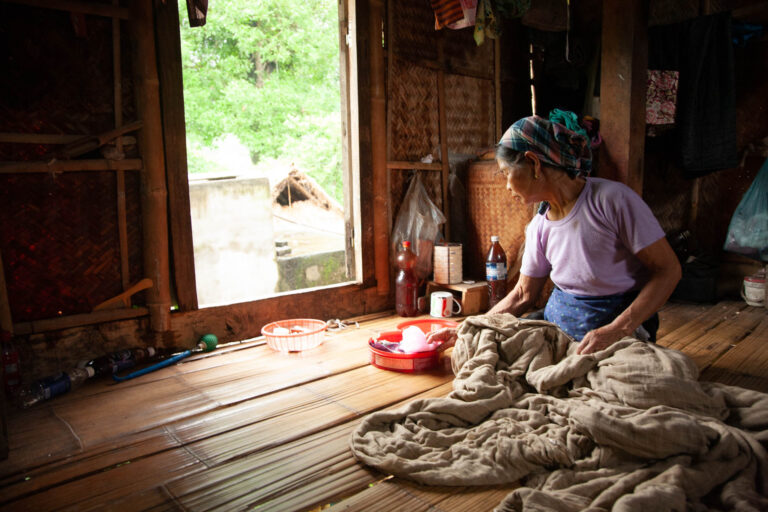 Old Vietnamese woman sewing textiles in Mai Chau, Vietnam